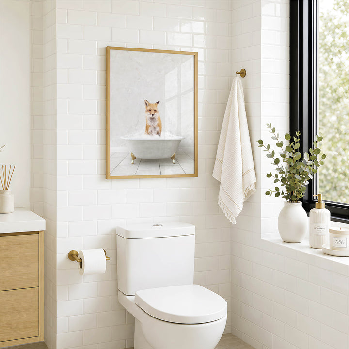 A framed image of a cat sitting in a bathtub is displayed on the wall above a white toilet in a bathroom.