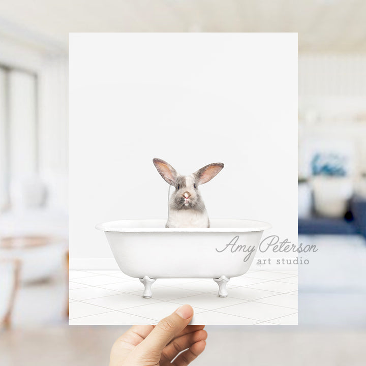 a person holding up a card with a picture of a bunny in a bathtub