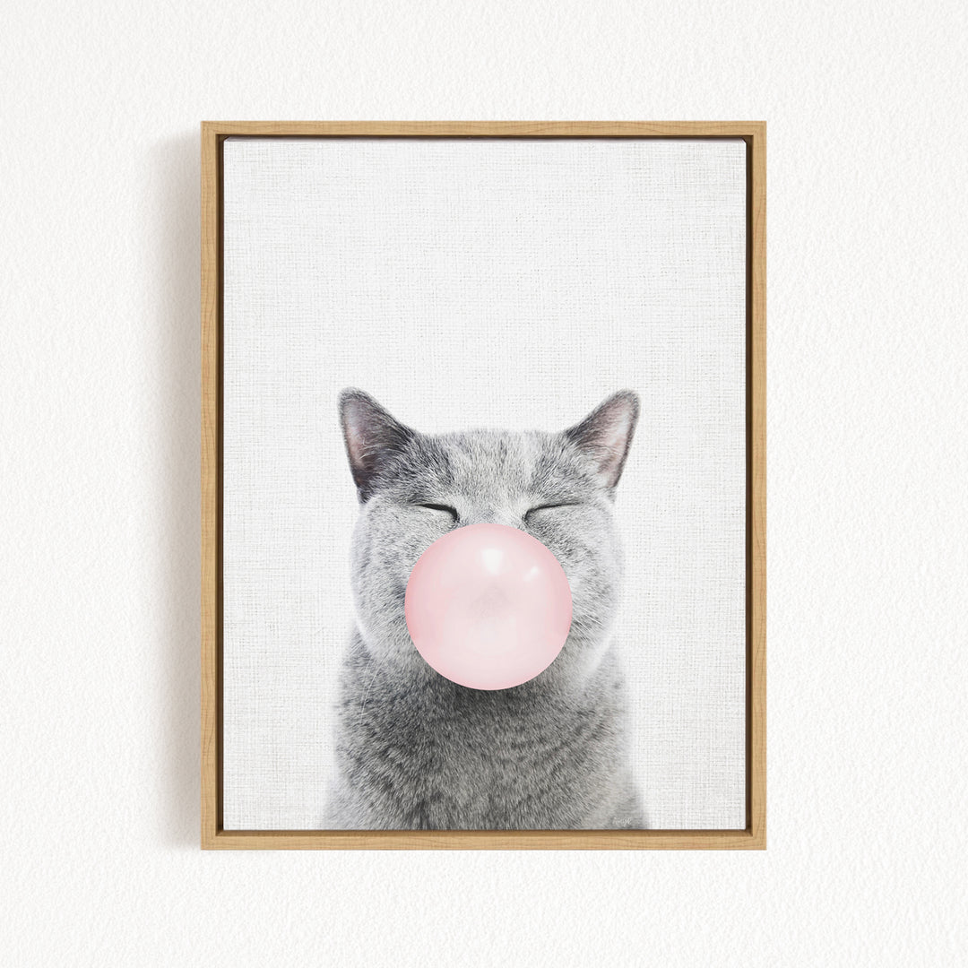 A gray cat blowing a pink bubble with its mouth.