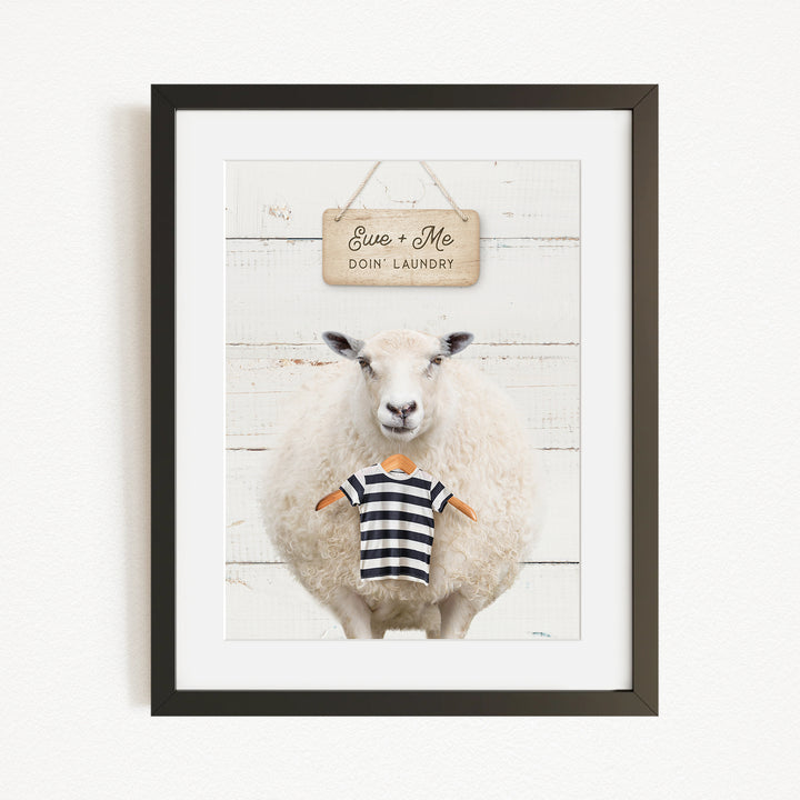 A framed image of a sheep wearing a striped shirt, with a sign above it that says "Euse + Me Doin Laundry".