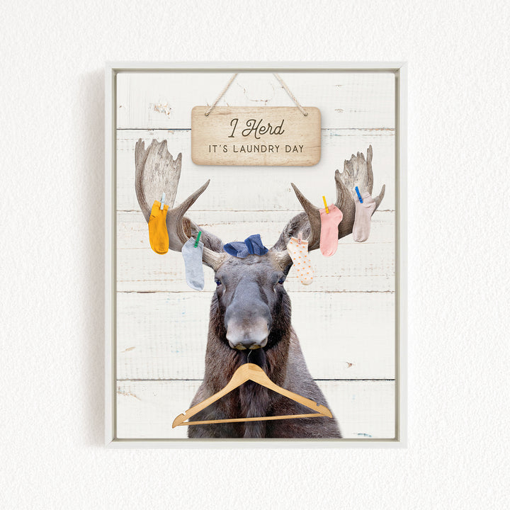 A framed image depicting a moose with a sign above it that says "I herd, it's laundry day".