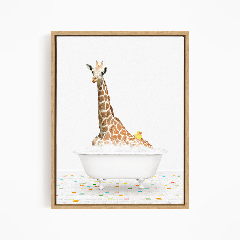 A giraffe is sitting in a white bathtub filled with bubbles, with a yellow duck floating on the water.