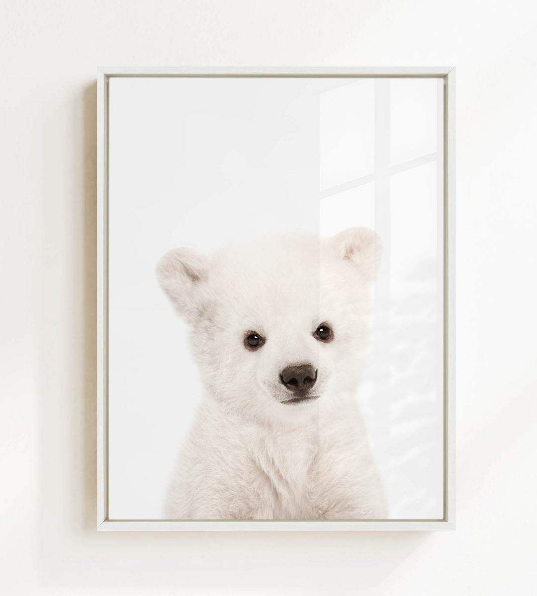 A cute white polar bear cub with large eyes and a black nose is the focus of the image.