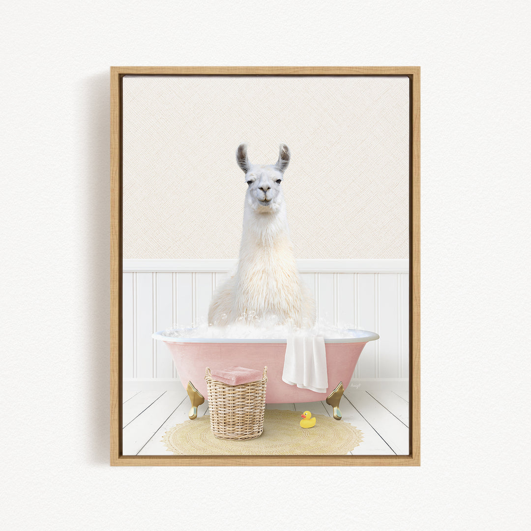 A white llama sitting in a pink bathtub filled with bubbles, surrounded by a basket of bath toys and a yellow rubber duck.