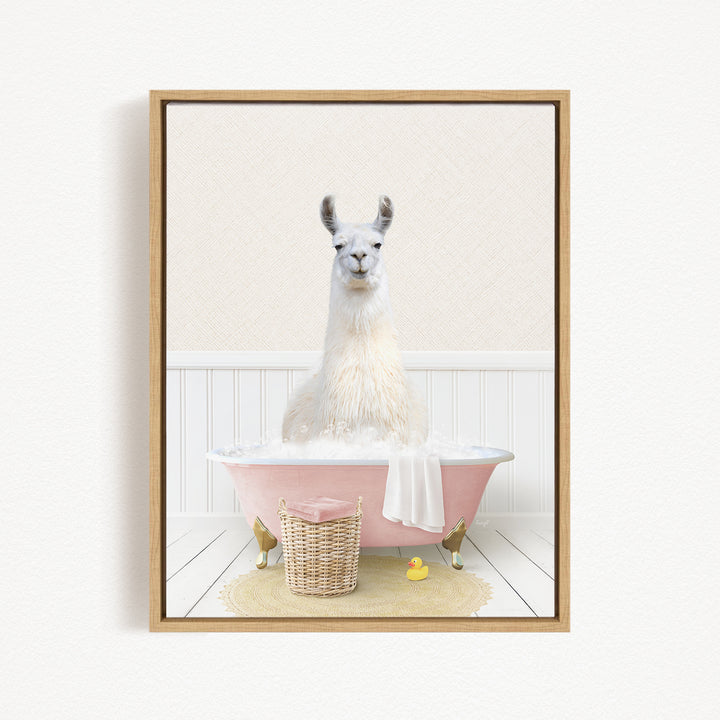 A white llama sitting in a pink bathtub filled with bubbles, surrounded by a basket of bath toys and a yellow rubber duck.
