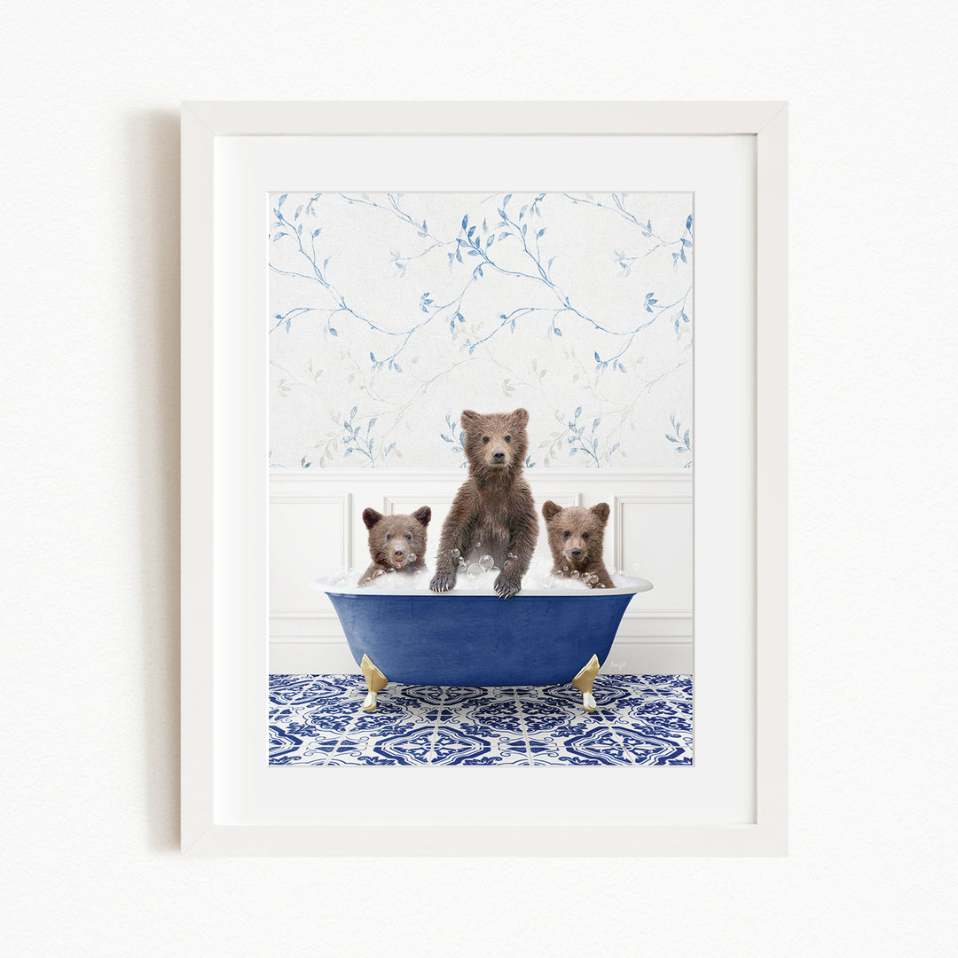 A framed image depicting three brown bears sitting in a blue bathtub, with a patterned tile floor and a floral wallpaper in the background.