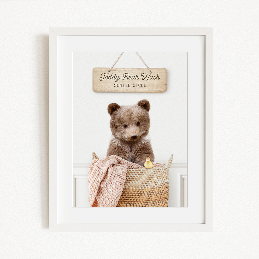 A framed image of a teddy bear sitting in a basket, with a sign above it that reads "Teddy Bear Wash Gentle Cycle".