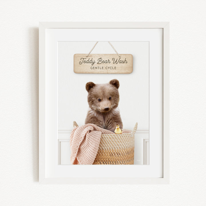 A framed image of a teddy bear sitting in a basket, with a sign above it that reads "Teddy Bear Wash Gentle Cycle".