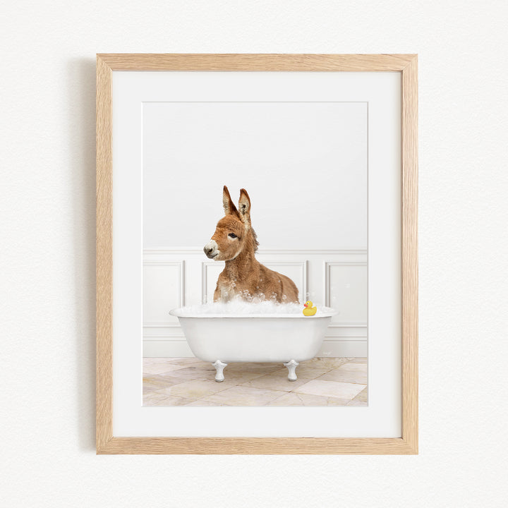 A donkey is sitting in a white bathtub filled with water, with a yellow rubber duck floating in the water.