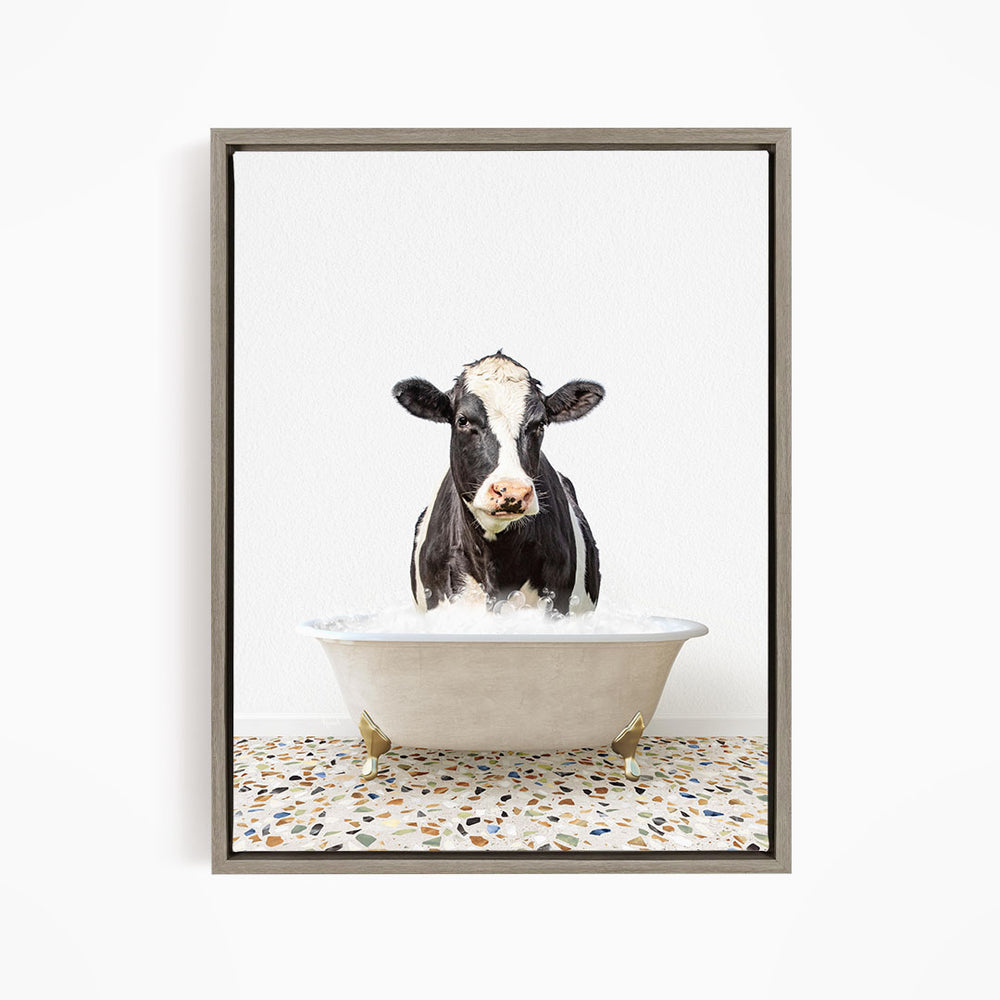 A black and white cow standing in a white bathtub filled with water, creating a whimsical and humorous scene.