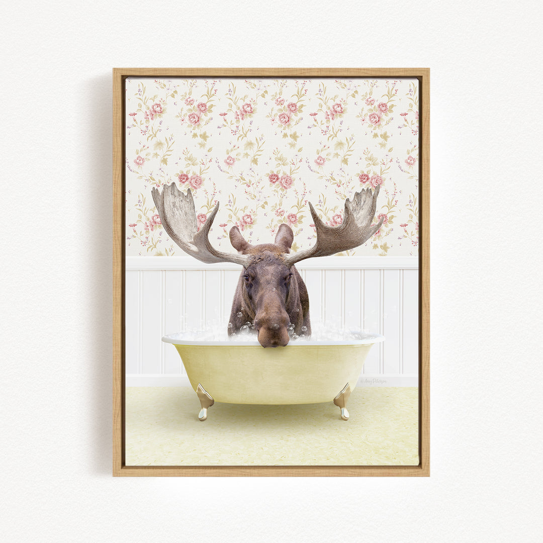 A moose with large antlers is sitting in a bathtub filled with water, surrounded by a floral wallpaper.