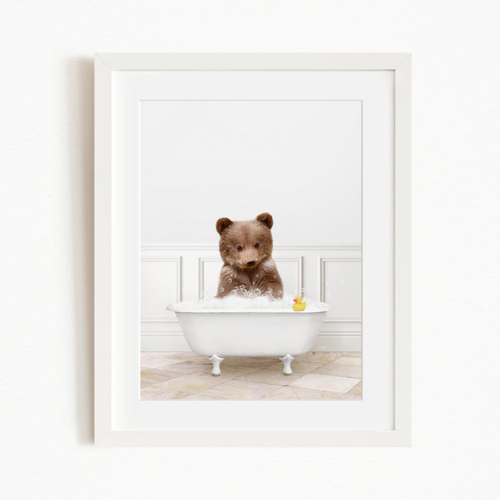 A brown bear sitting in a white bathtub filled with water, with a yellow rubber duck floating in the water.