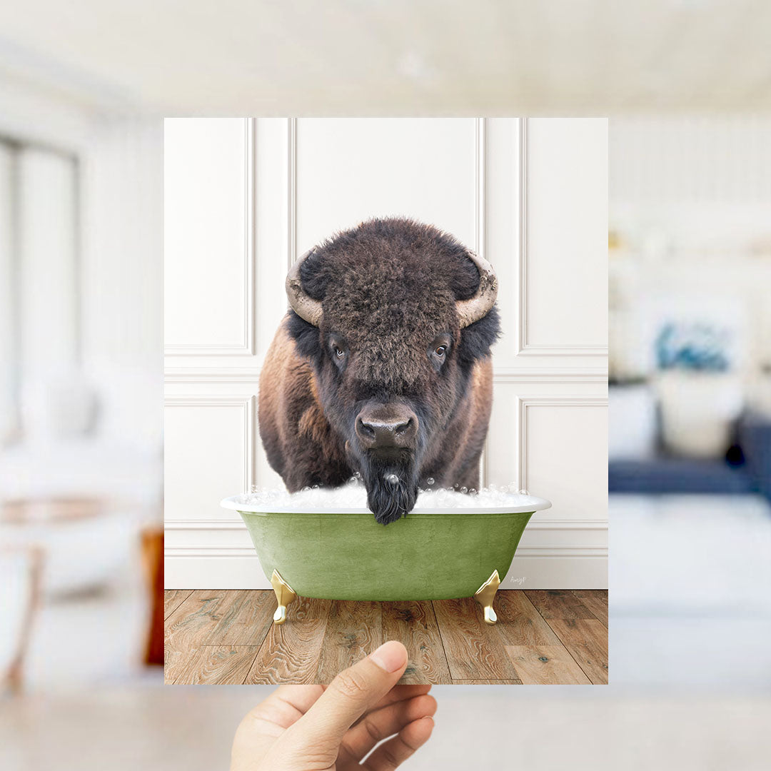 A large, furry bison with horns is sitting in a green bathtub, appearing to enjoy the bath.