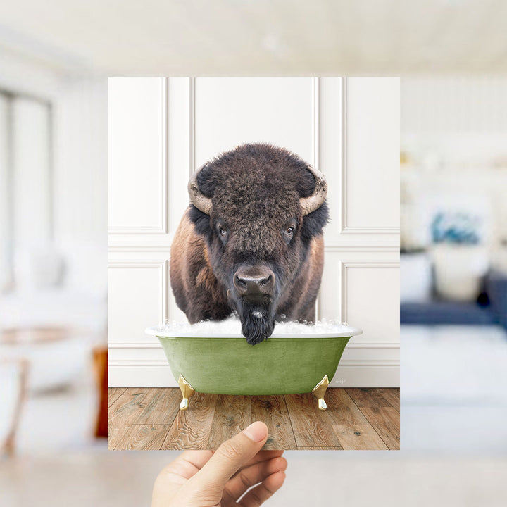 A large, furry bison with horns is sitting in a green bathtub, appearing to enjoy the bath.