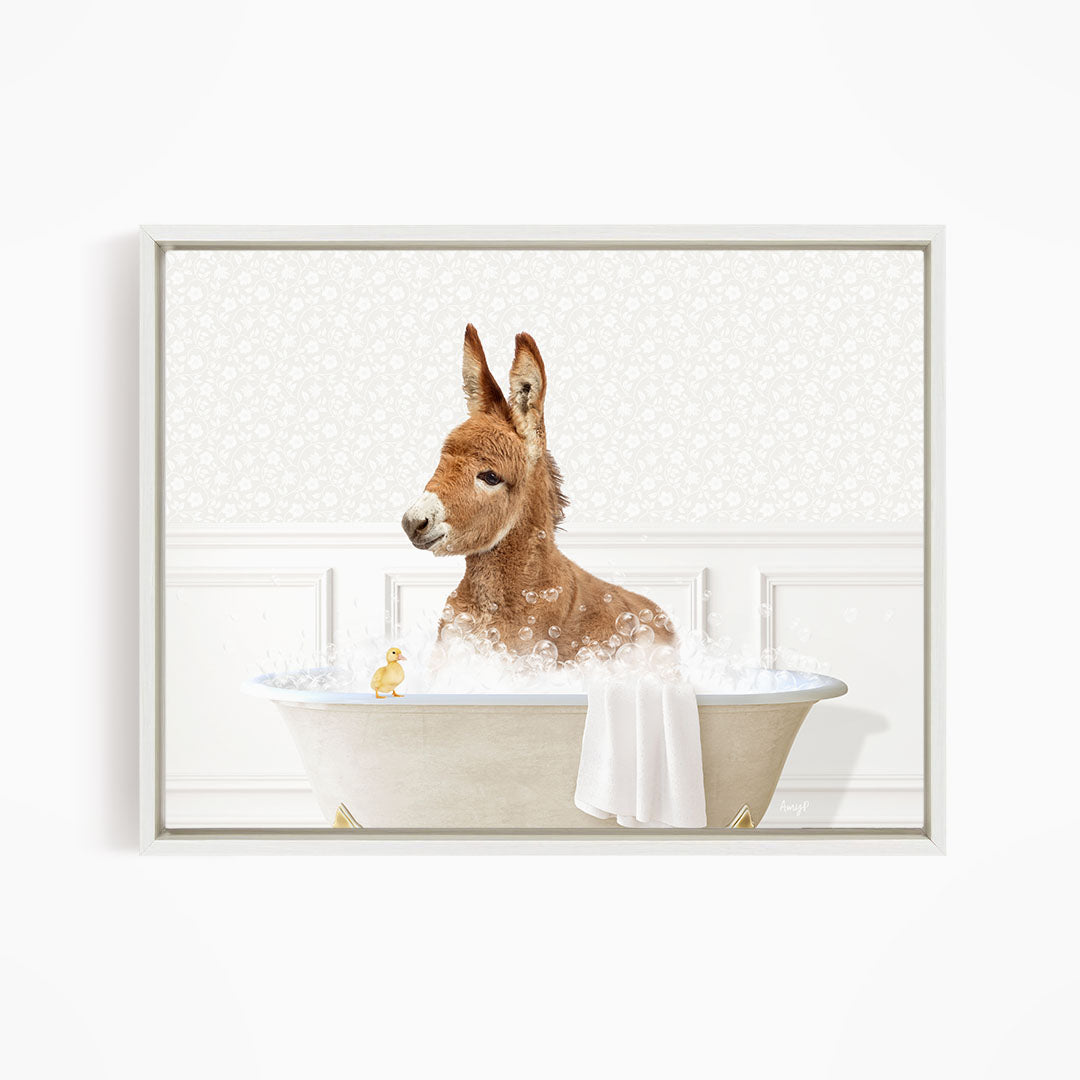 A brown donkey is sitting in a bathtub filled with water, surrounded by a towel and a small yellow duck.