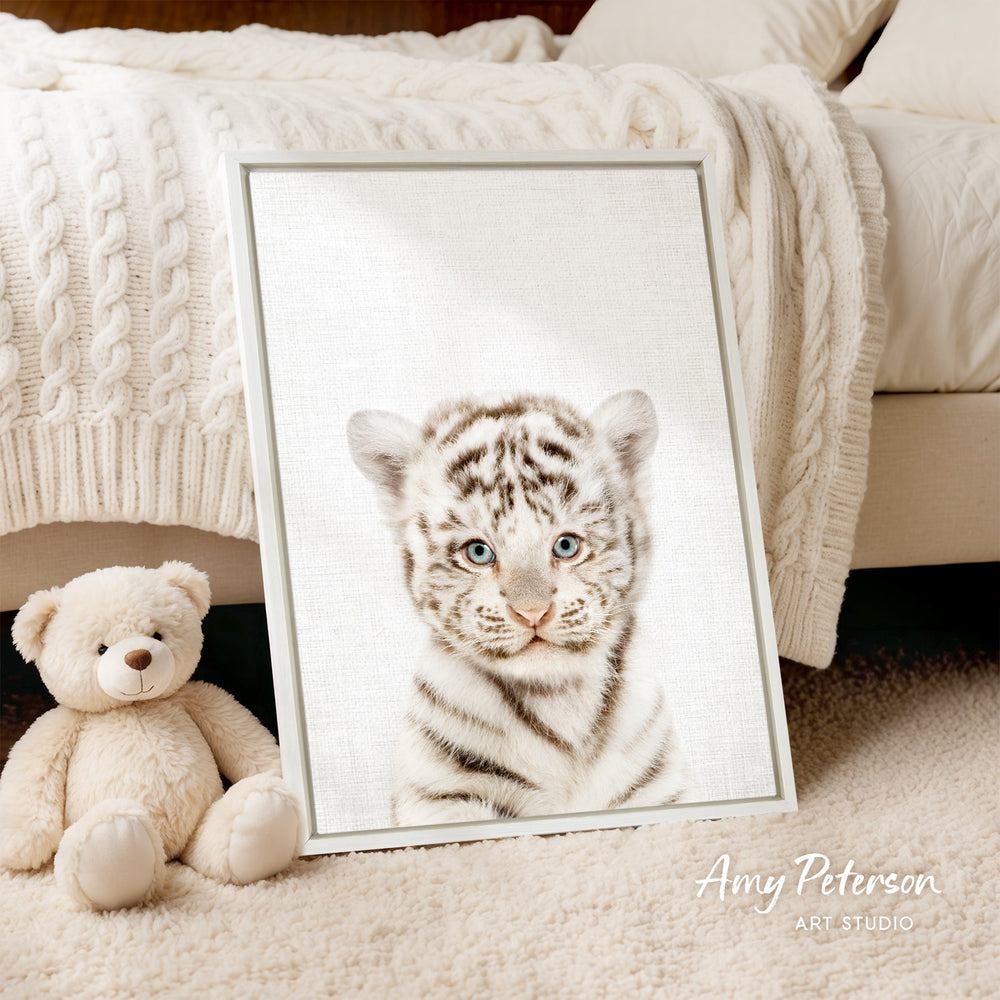 A framed photograph of a tiger cub is displayed on a bed, accompanied by a teddy bear.