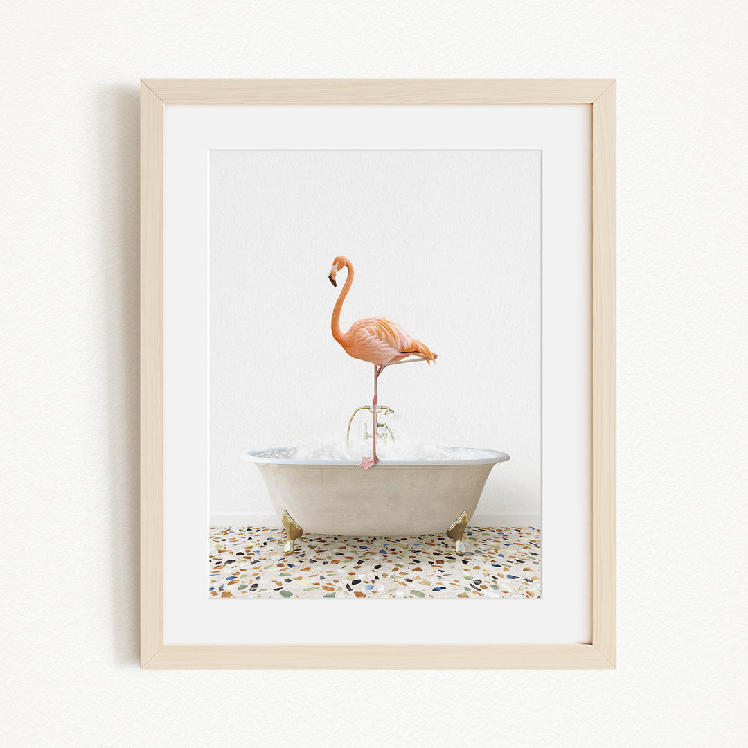 A framed image of a pink flamingo standing on one leg in a white bathtub filled with water.