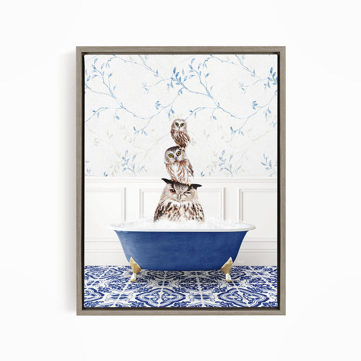 A framed image depicting a group of owls sitting in a blue bathtub, with a patterned tile floor and a floral wallpaper in the background.