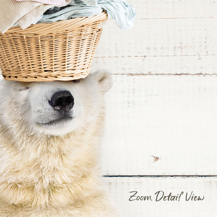 A polar bear is sitting on a wooden surface with a basket of clothes on its head.
