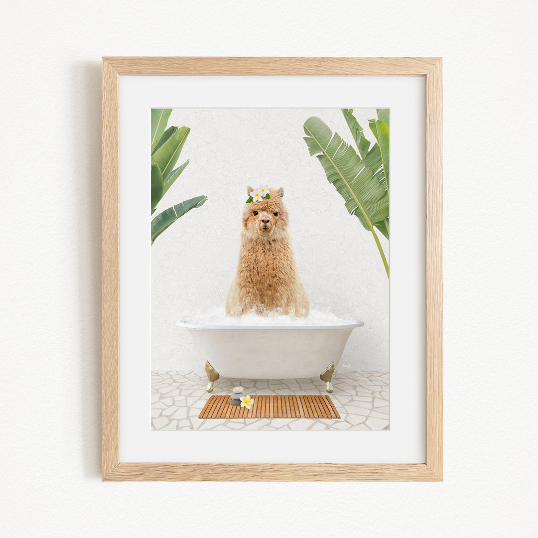 A brown alpaca sitting in a white bathtub filled with bubbles, surrounded by green plants and a wooden mat on the floor.
