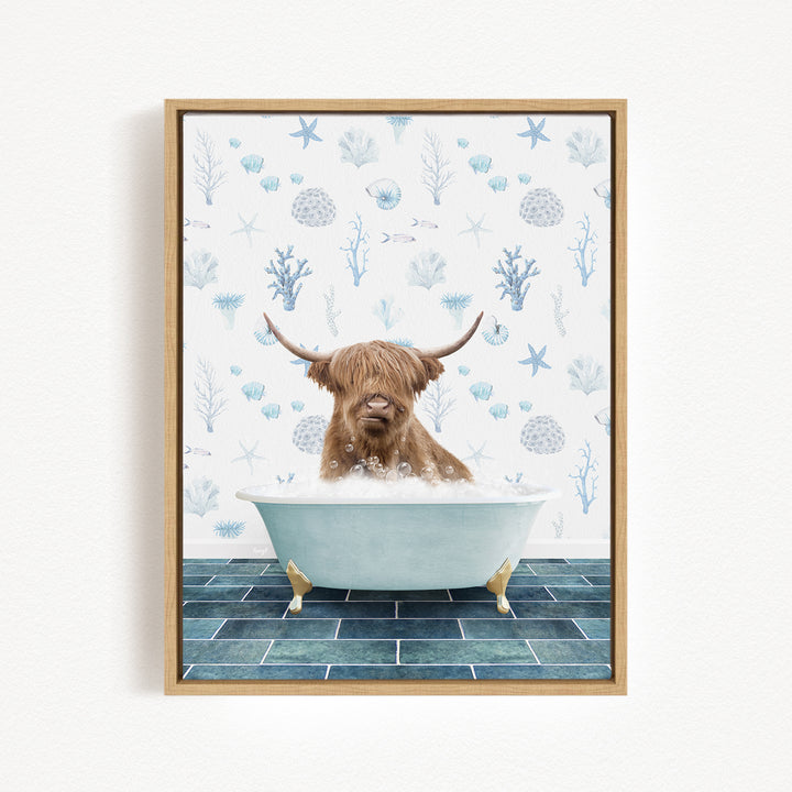 A brown cow with long horns is sitting in a bathtub filled with bubbles, surrounded by a blue and white floral pattern on the wall behind it.