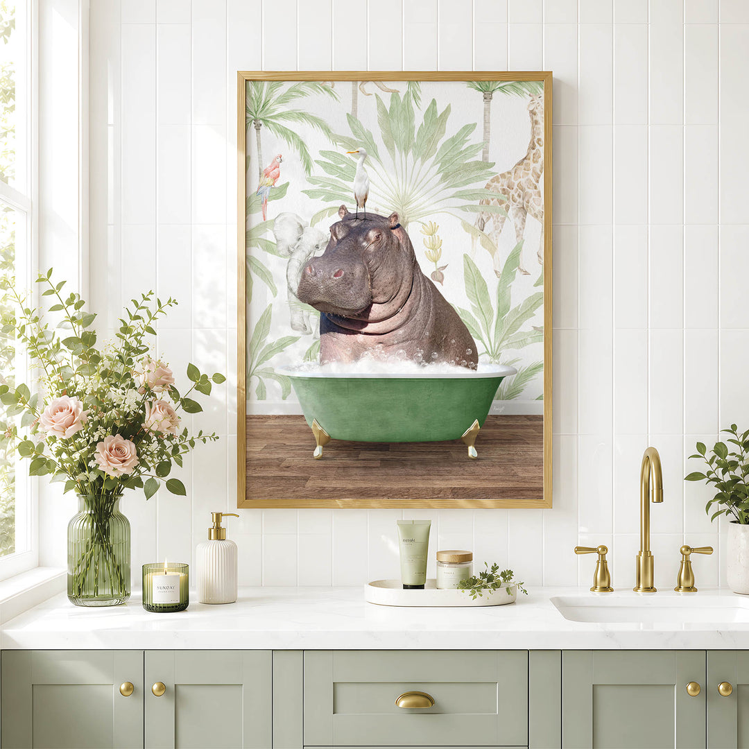 A framed image of a hippopotamus sitting in a green bathtub, surrounded by tropical foliage, is displayed on a white tiled wall above a bathroom counter with various toiletries and decorative items.