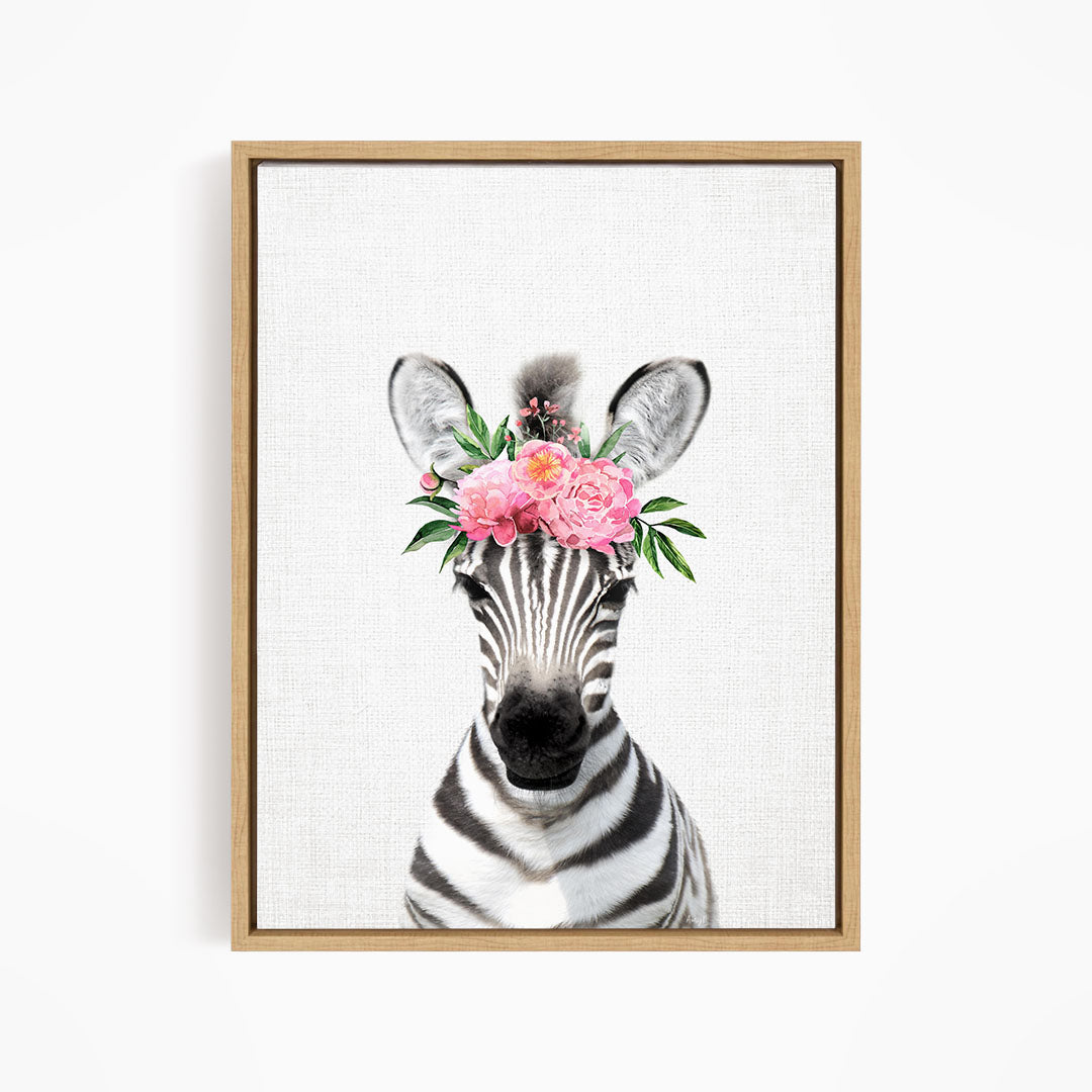 A zebra wearing a floral headpiece with pink flowers and green leaves.