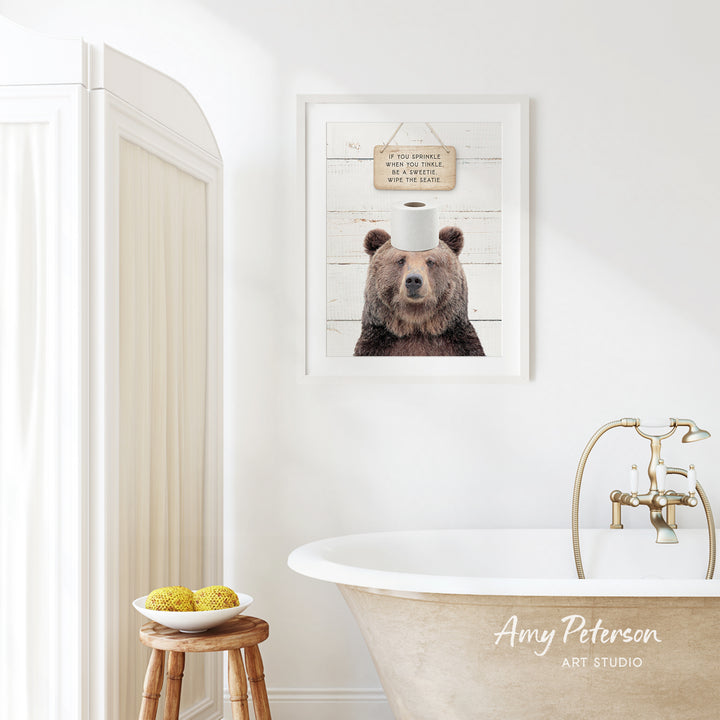 a bathroom with a framed picture of a bear wearing a sign that says "If you sweated when you sweated, you'll be happy when you're happy". The bathroom has a clawfoot bathtub, a wooden stool, and a bowl of fruit on the stool.