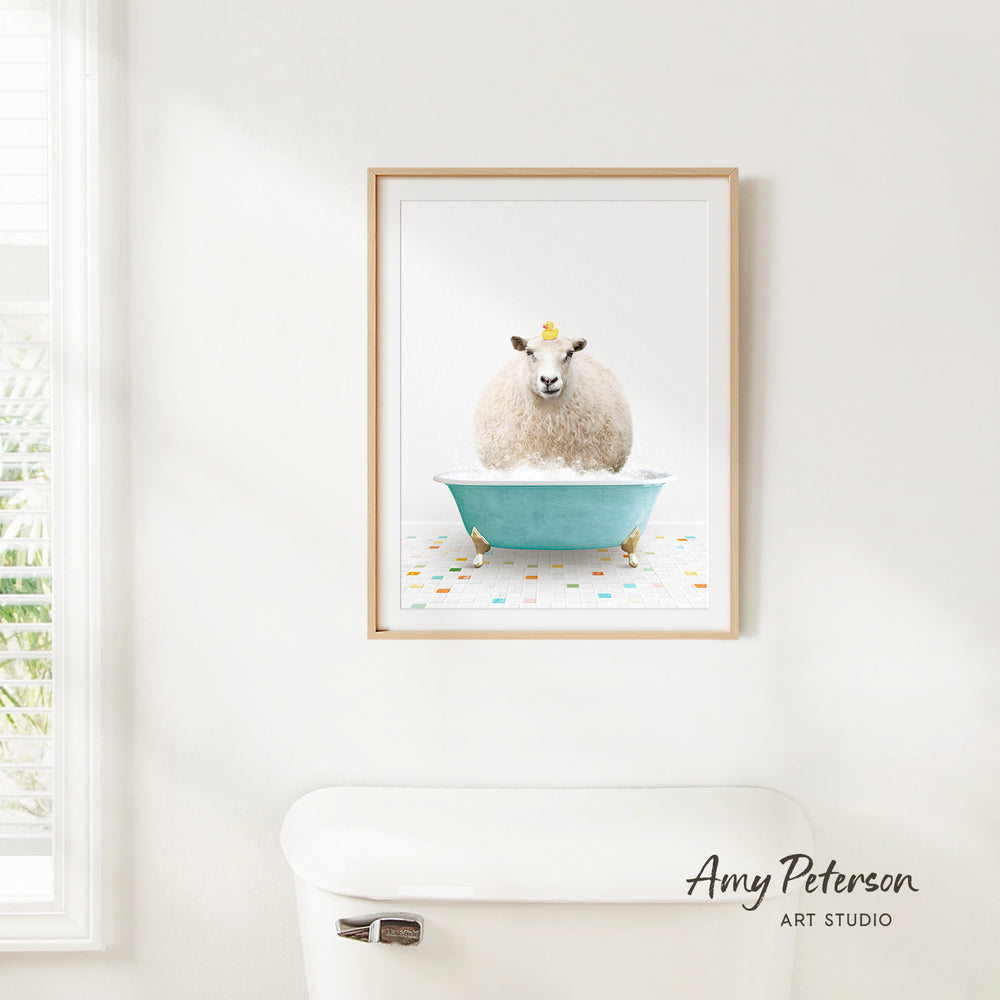 A framed image of a sheep sitting in a blue bathtub, with a yellow crown on its head, is hanging on a white wall.