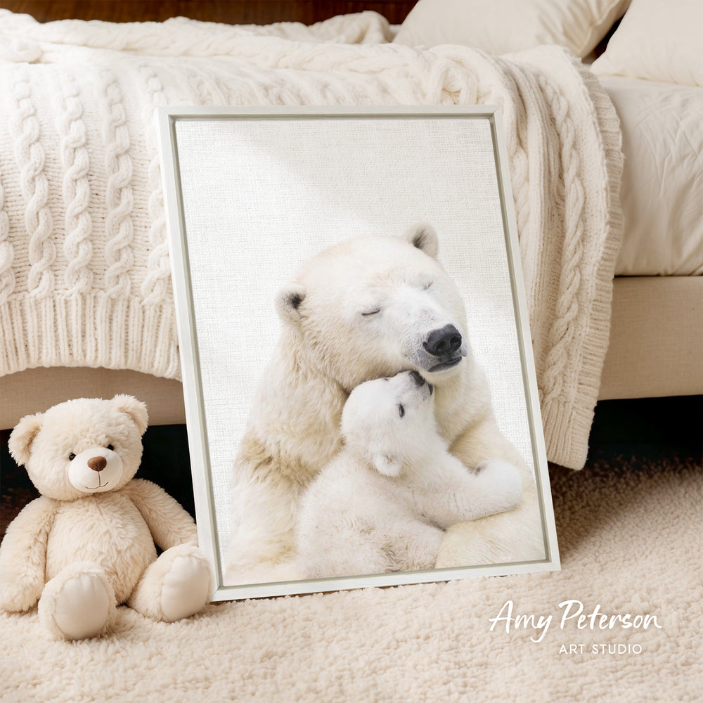 A framed photograph of a polar bear and its cub resting together, with a teddy bear sitting next to it on the floor.