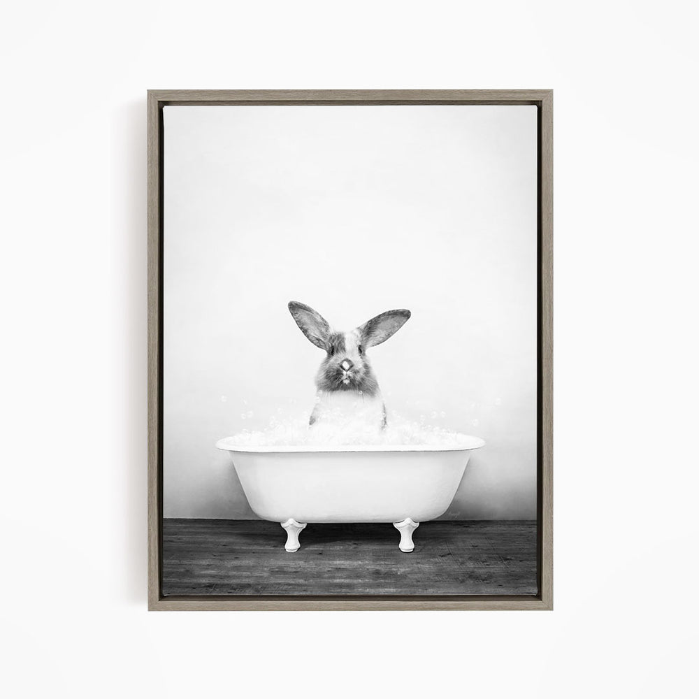 A rabbit sitting in a white bathtub filled with water, looking directly at the camera.