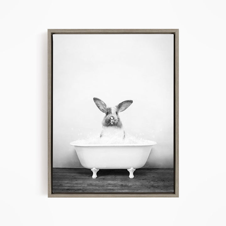 A rabbit sitting in a white bathtub filled with water, looking directly at the camera.