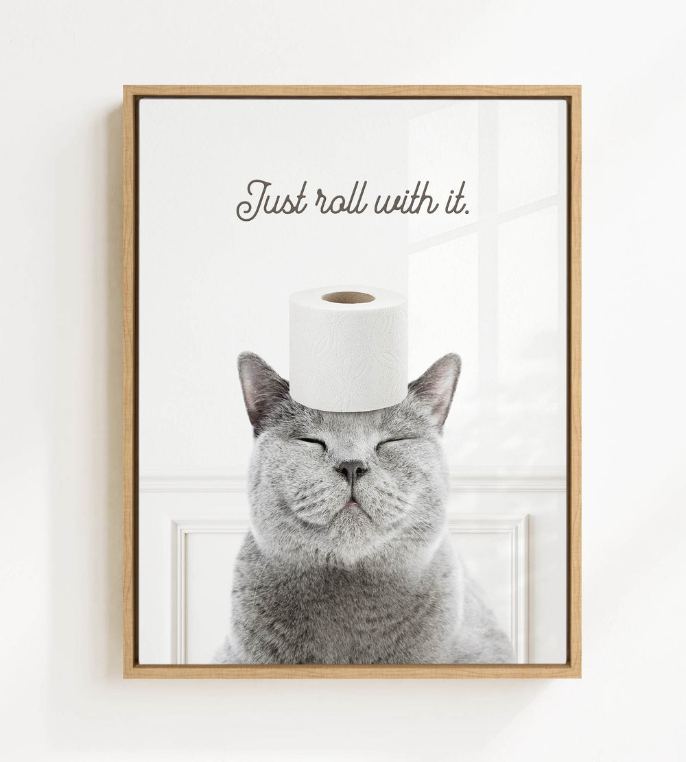 A gray cat with its eyes closed and a roll of toilet paper on its head, with the text "Just roll with it."