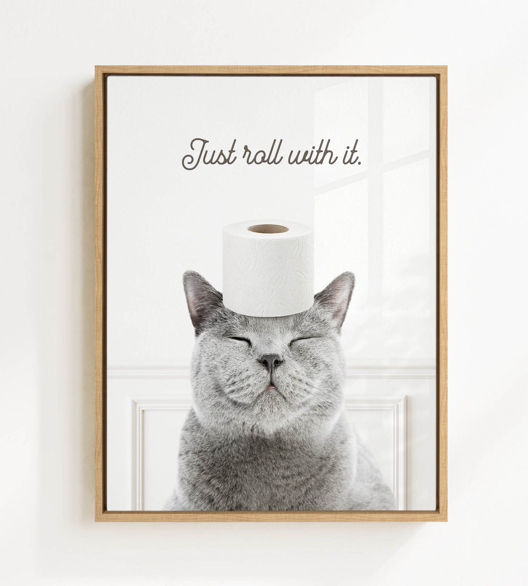 A gray cat with its eyes closed and a roll of toilet paper on its head, with the text "Just roll with it."