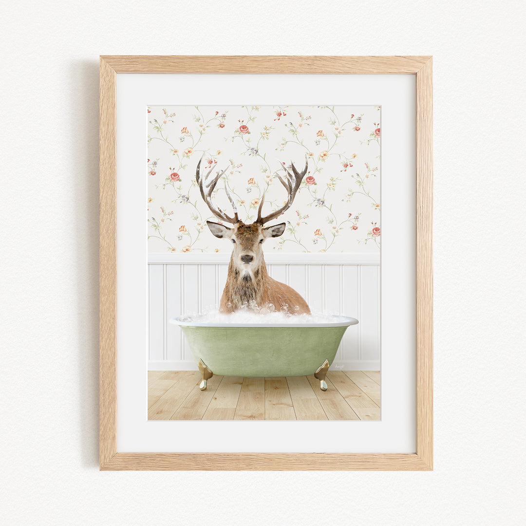 A deer with antlers is sitting in a green bathtub, surrounded by a floral wallpaper.