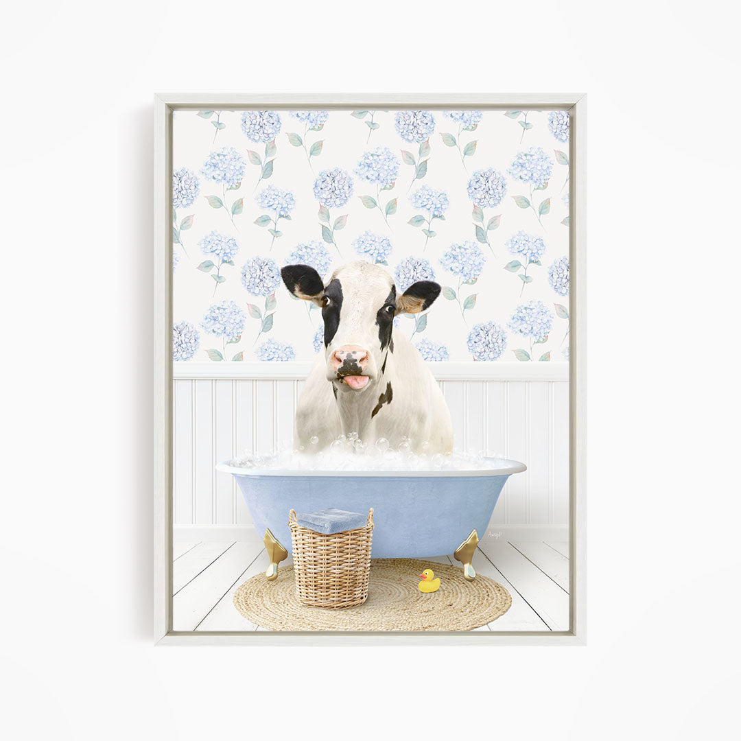 A cow is sitting in a blue bathtub filled with water, surrounded by a wicker basket and a yellow rubber duck.