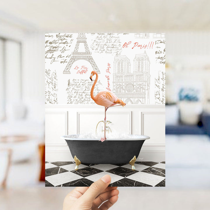 A hand is holding up a print featuring a pink flamingo standing on a black bathtub, with a wall decorated with the Eiffel Tower and other Parisian landmarks in the background.