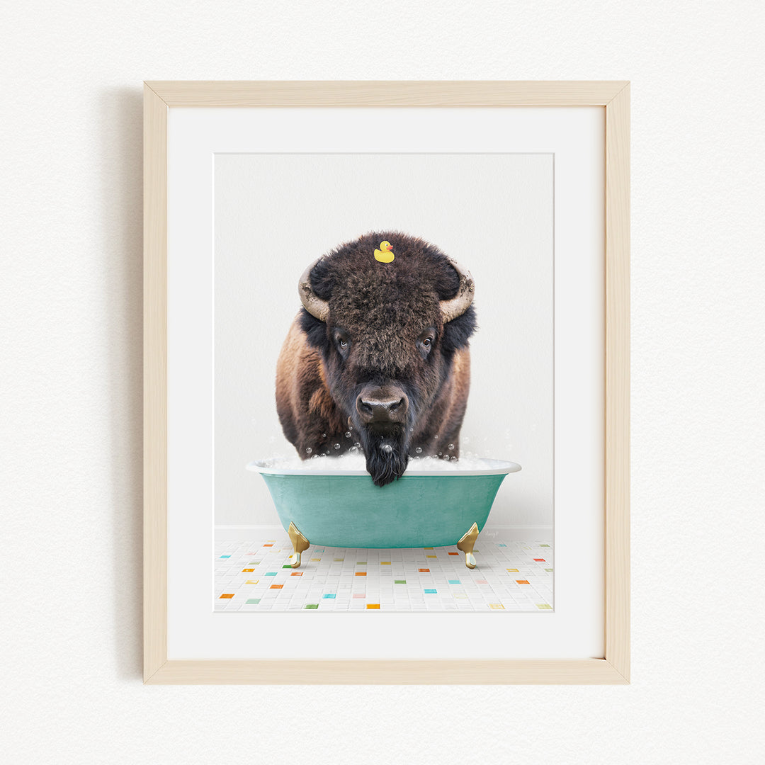 A buffalo with a yellow rubber duck perched on its head is sitting in a blue bathtub, surrounded by colorful tiles on the floor.