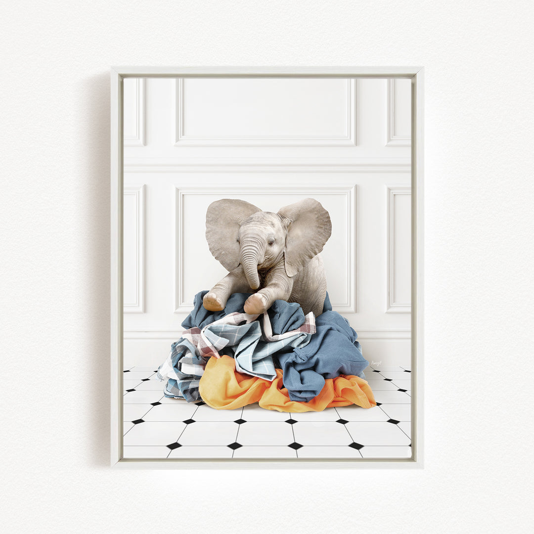 A stuffed elephant toy is sitting on a pile of clothes on a tiled floor.