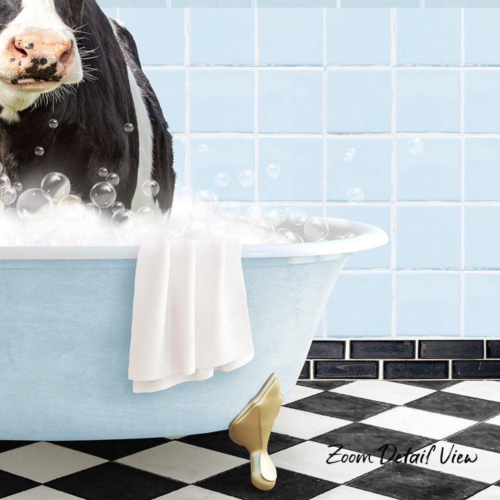 A cow is sitting in a bathtub filled with bubbles, with a towel and a gold shoe placed on the floor next to the tub.