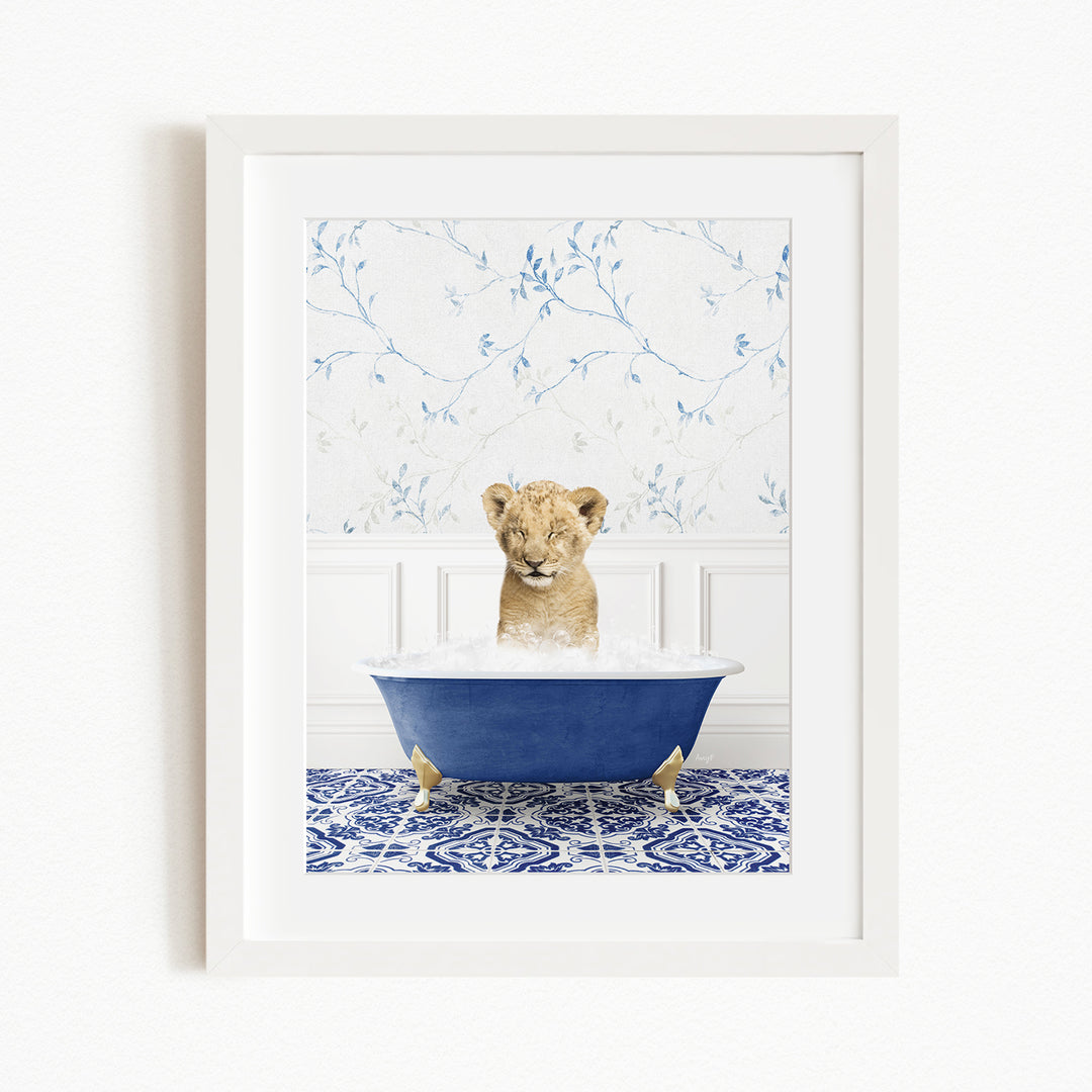 A young lion cub sitting in a blue bathtub filled with water, surrounded by a blue and white patterned rug.