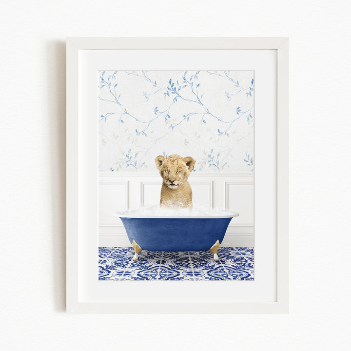A young lion cub sitting in a blue bathtub filled with water, surrounded by a blue and white patterned rug.