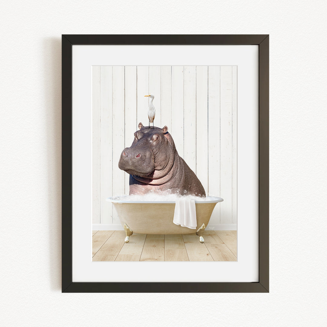 A framed image depicting a hippopotamus sitting in a bathtub, with a bird perched on its head.