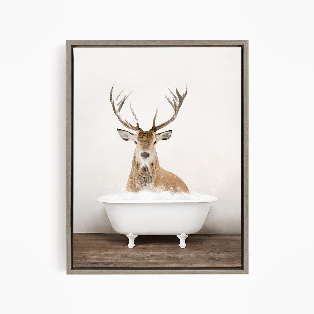 A deer with large antlers is sitting in a white bathtub filled with water, creating a whimsical and unexpected scene.
