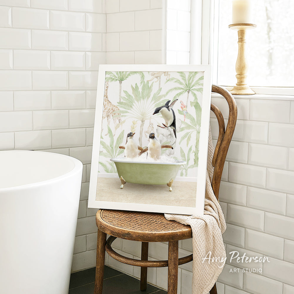 A framed print of a penguin bathtub with penguins sitting in it, displayed on a wooden chair in a bathroom setting.