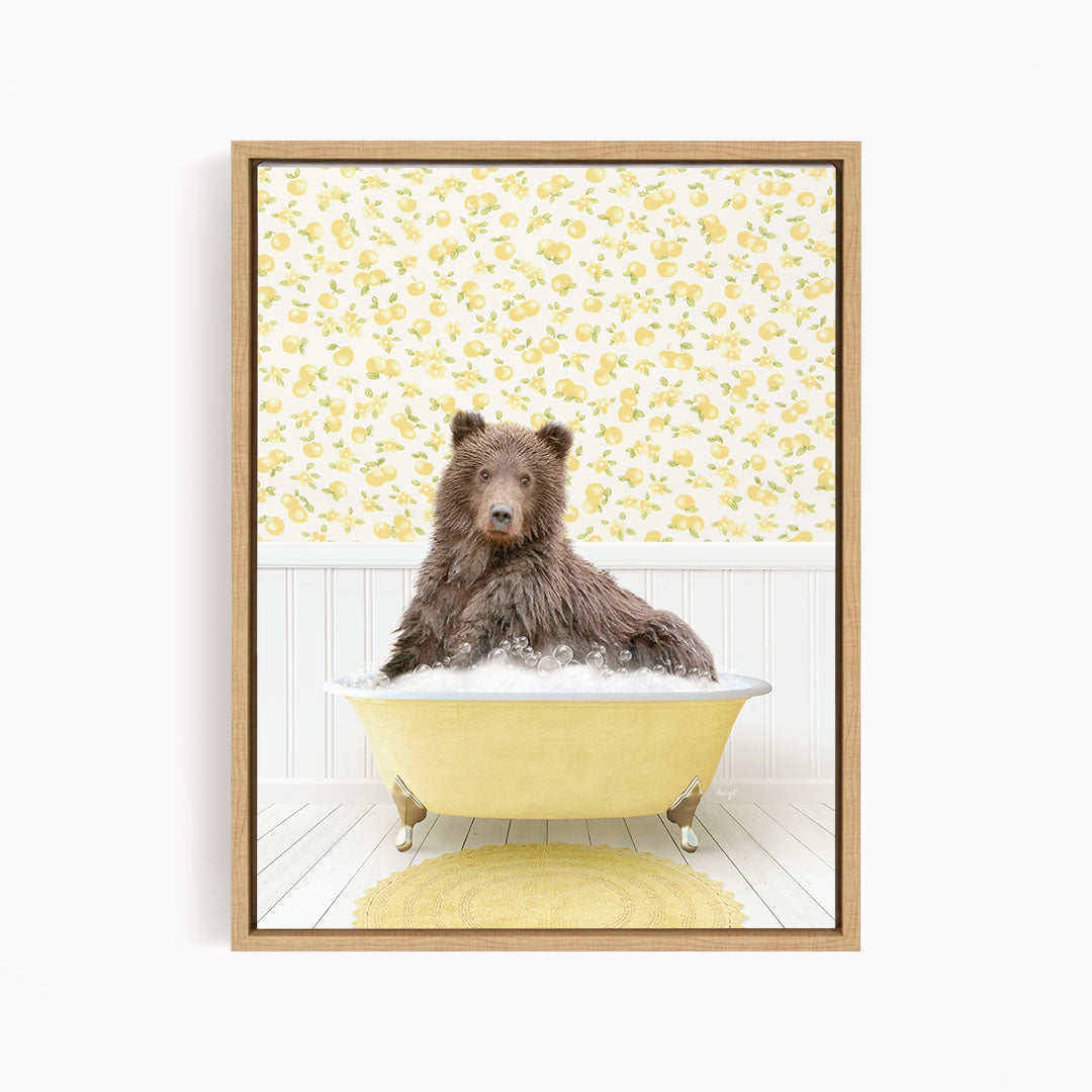 A brown bear sitting in a yellow bathtub filled with bubbles, surrounded by a yellow floral pattern on the wall behind it.