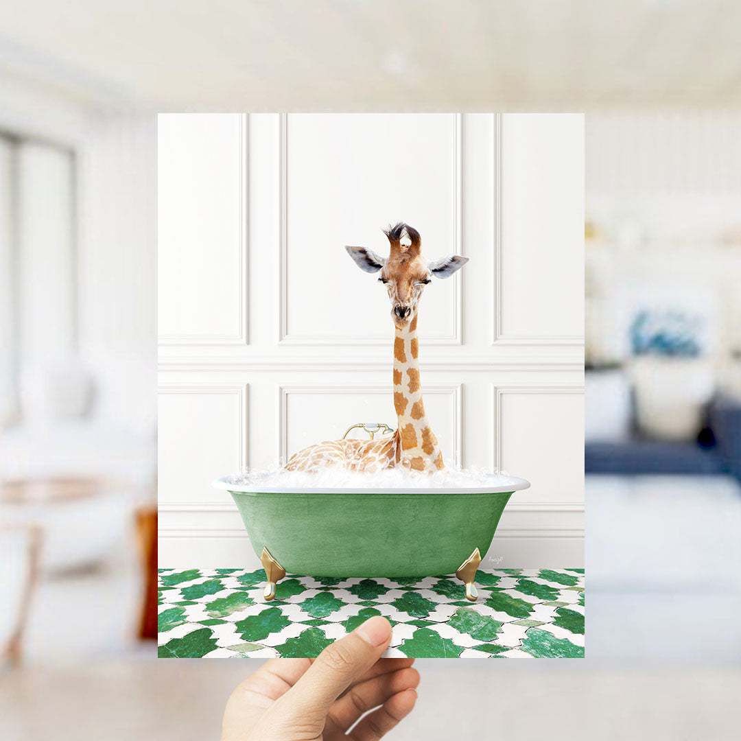 A giraffe sitting in a green bathtub filled with bubbles, with a hand holding the photo up to the camera.