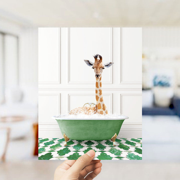 A giraffe sitting in a green bathtub filled with bubbles, with a hand holding the photo up to the camera.