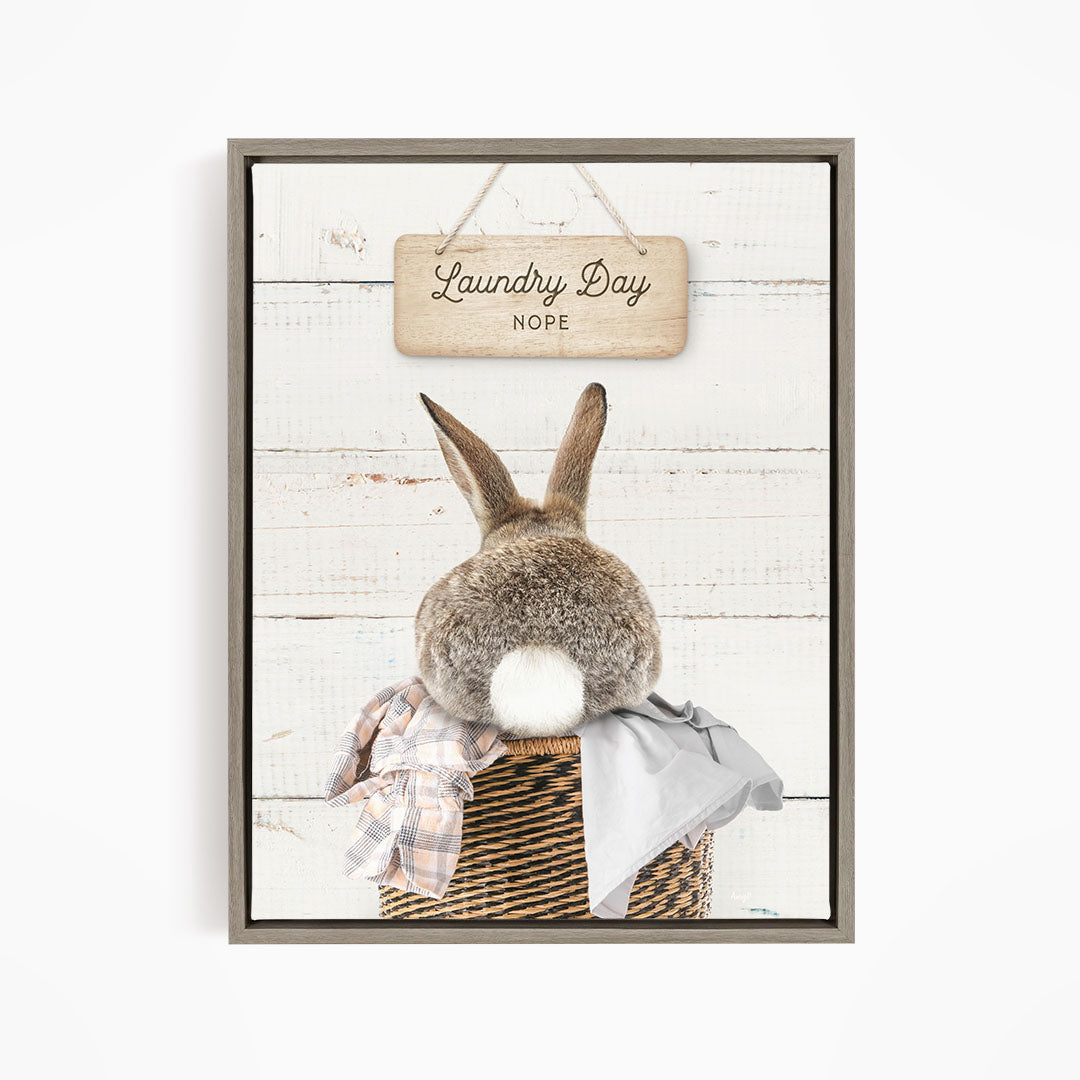 A wooden sign with the text "Laundry Day Hope" hangs above a basket containing a plaid blanket and a gray garment.