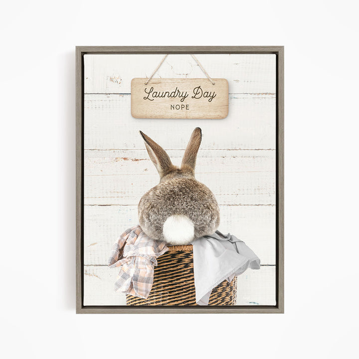 A wooden sign with the text "Laundry Day Hope" hangs above a basket containing a plaid blanket and a gray garment.